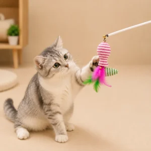 Kitten playing with the pink fish-shaped feather wand attachment