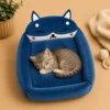 Blue fox-shaped cat bed with a striped kitten sleeping inside